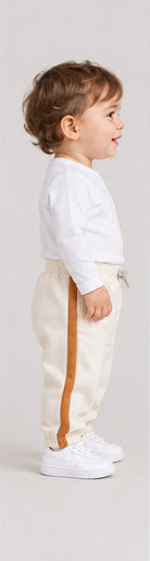 Left side view of boys' ivory baby sweatpants with caramel side stripes on an infant boy
