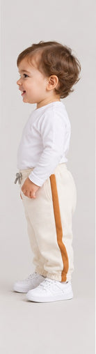 Right side view of boys' ivory baby sweatpants with caramel side stripes on an infant boy