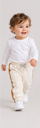 Lifestyle view of boys' ivory baby sweatpants with caramel side stripes on an infant boy